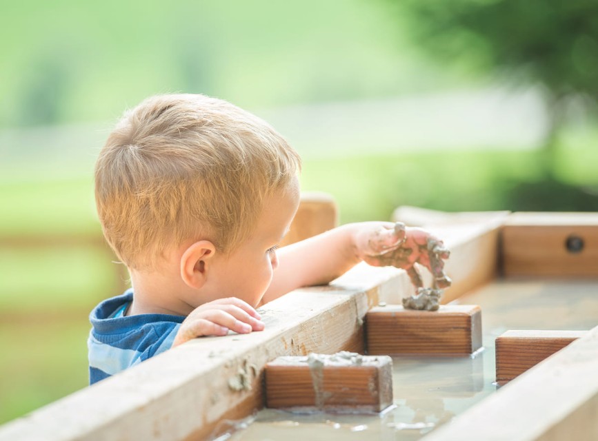Kinder entdecken Wasser, Sand und Naturmaterialien im Abenteuerland Kleinarl
