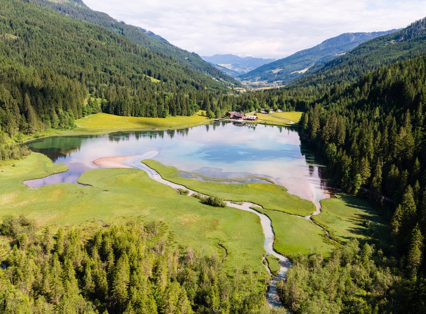 Luftaufnahme des Jägersees in Kleinarl mit klarem Wasser, Almwiesen und umliegenden Bergen © Wagrain-Kleinarl Tourismus/Eduardo Gellner