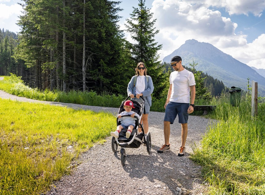 Familie spaziert den Family Run in Kleinarl entlang mit Kinderwagen und Bergblick © Shuttleberg Bergbahnen/Markus Fischer