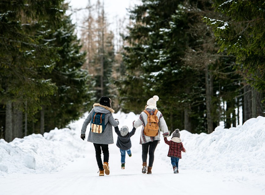 Familie spaziert gemeinsam durch den tief verschneiten Winterwald in Kleinarl – ein entspanntes Naturerlebnis für Groß und Klein © Shutterstock