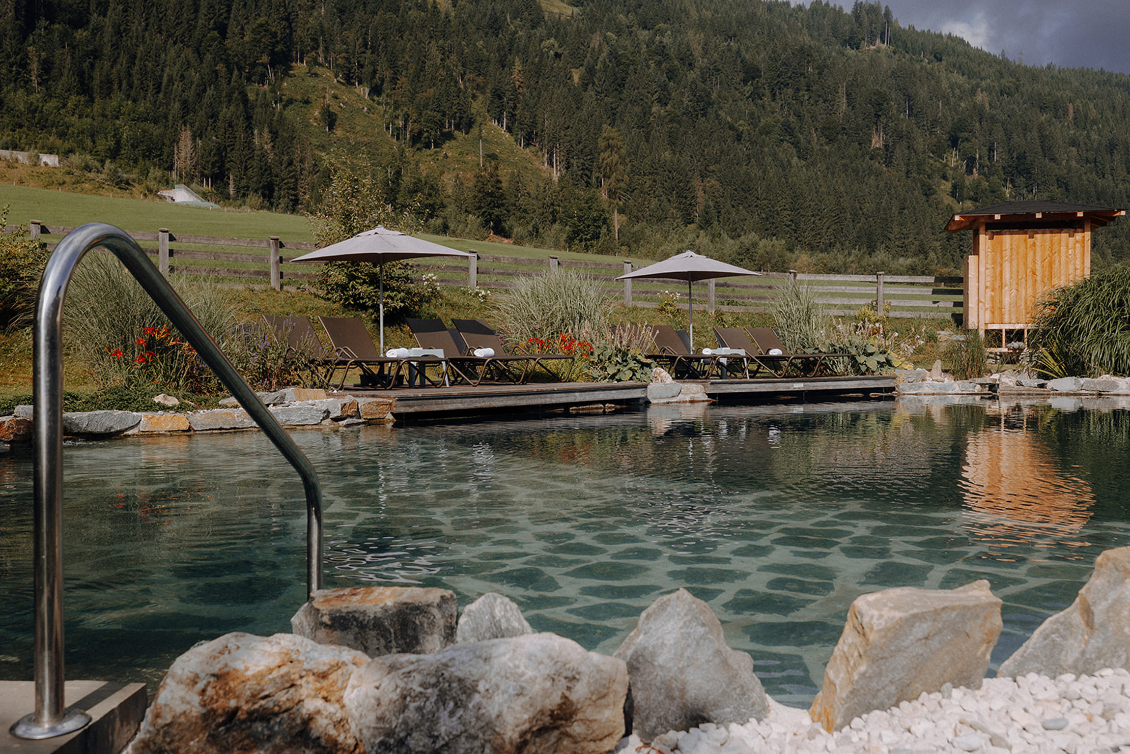 Naturbadeteich im Familienhotel Botenwirt mit Liegen und Bergblick