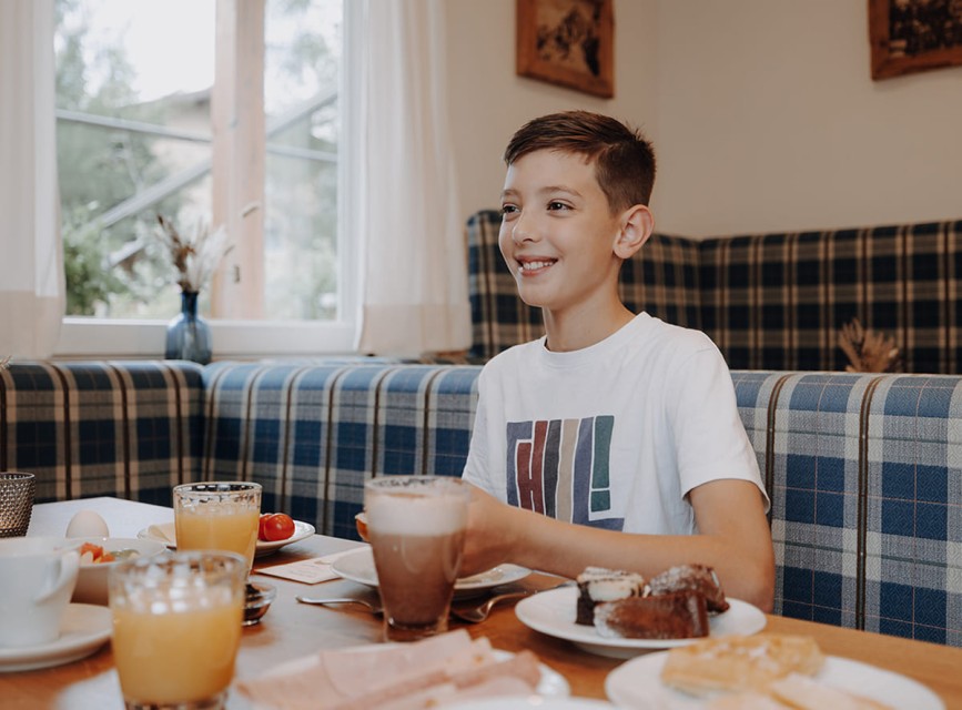 Kind genießt das Frühstück im Hotel Botenwirt mit Saft und Kakao