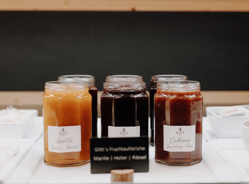 Gläser mit verschiedener Marmelade, beschriftet als Marille, Holler und Erdbeere