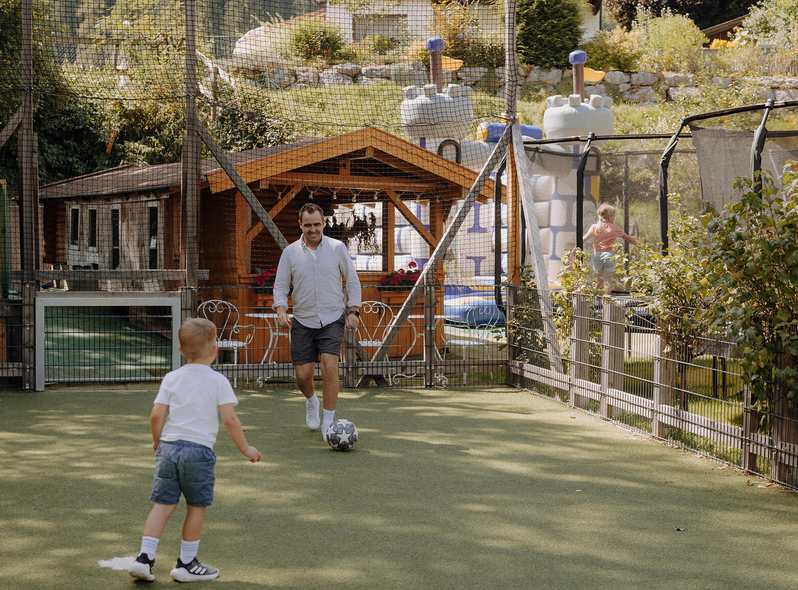 Vater und Kind beim gemeinsamen Fu&szlig;ballspielen auf dem Hotelspielplatz