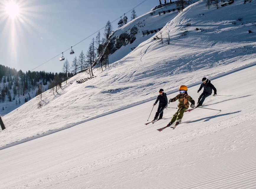 Familie beim gemeinsamen Skifahren auf perfekt präparierten Pisten in Ski amadé © 2025 JO Salzburg