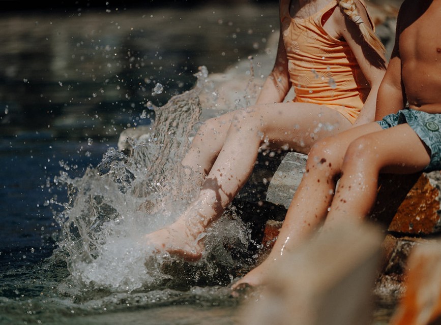 Kinder planschen und spielen am Naturbadeteich im Familienhotel Botenwirt