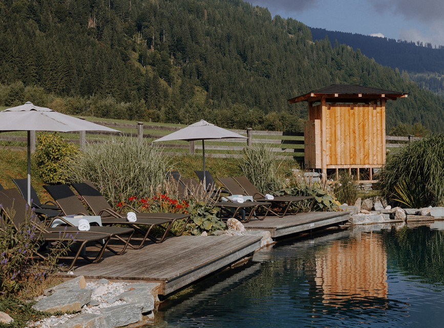 Liegest&uuml;hle und Sonnenschirme am Naturbadeteich des Familienhotels Botenwirt in Kleinarl